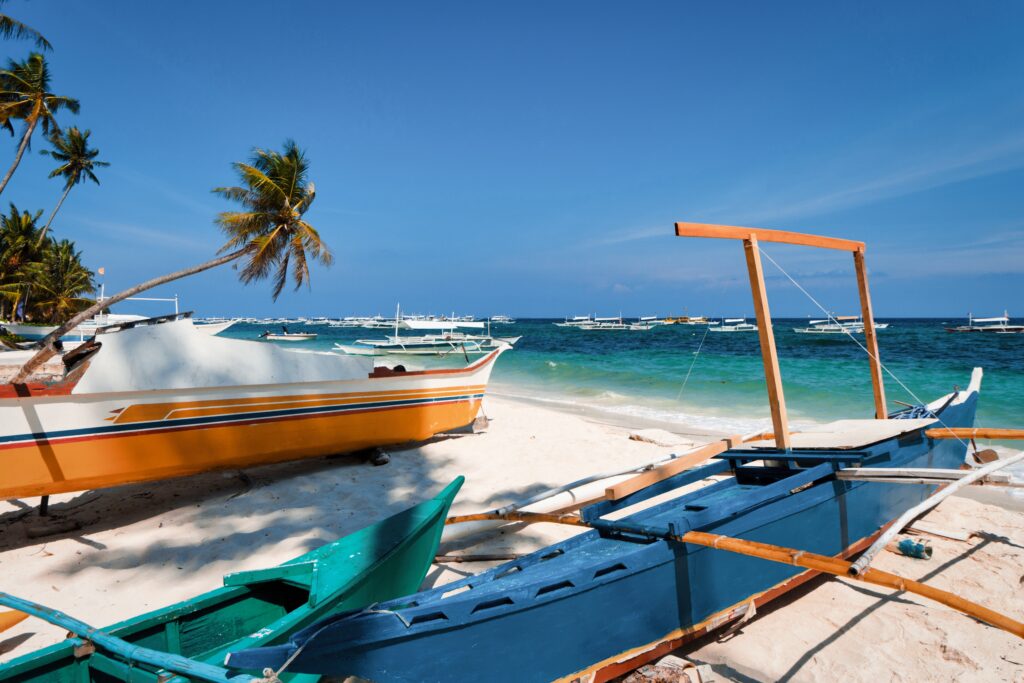 Am Alona Beach auf Bohol reihen sich die Boote am Strand Alona Beach aneinander.