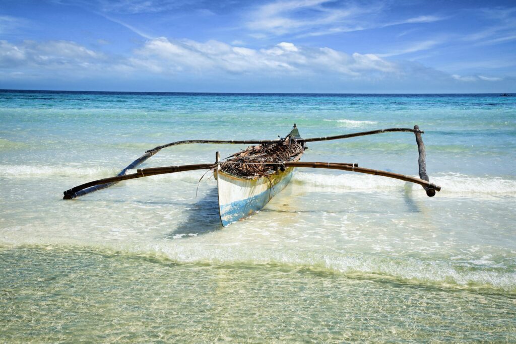 Ein altes Kanu aus Holz liegt an der Küste am Meer von Anda auf Philippinens Insel Bohol.