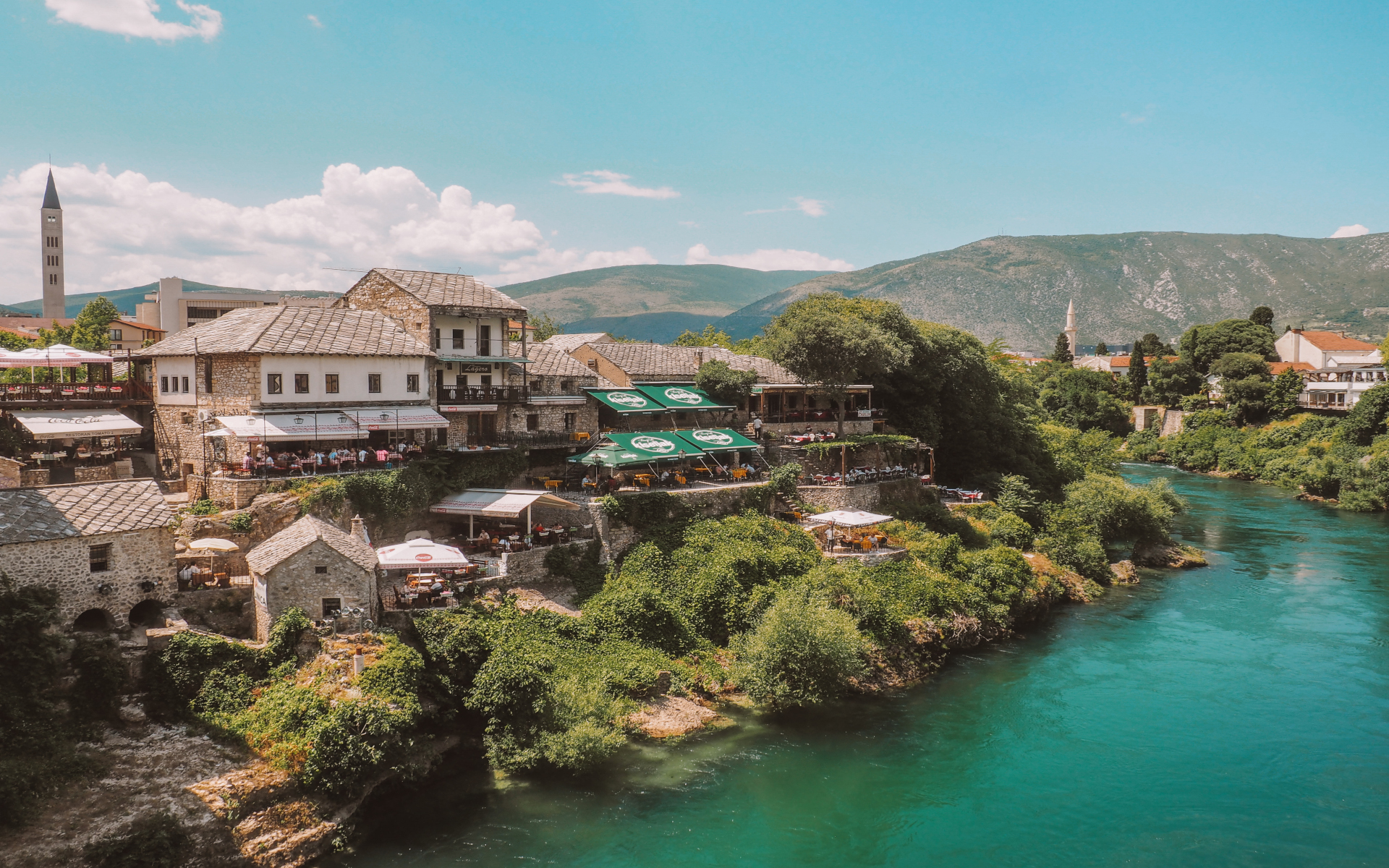 Ein satt-türkiser Fluss schlängelt sich entlang eines Dorfes in Bosnien und Herzegowina.