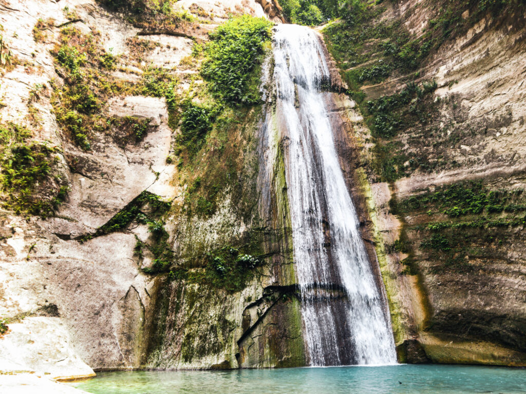 ein großer Wasserfall fließt einen hohen Felsen hinunter.