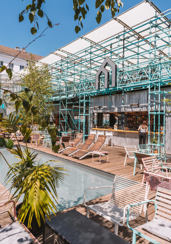 Der Manifesto Anděl Food Market von außen mit bunten Stühlen und einem kleinen Pool in Prag.
