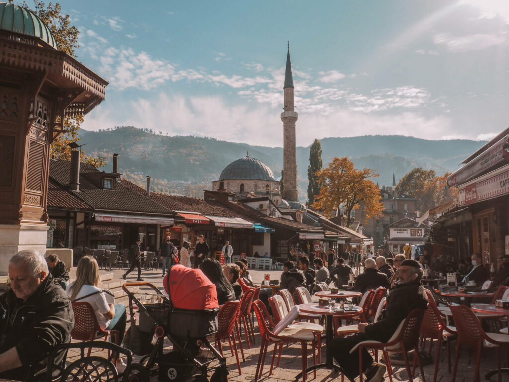 Einheimische und Touristen genießen auf einem Platz die Sonne in der Altstadt von Sarajevo.